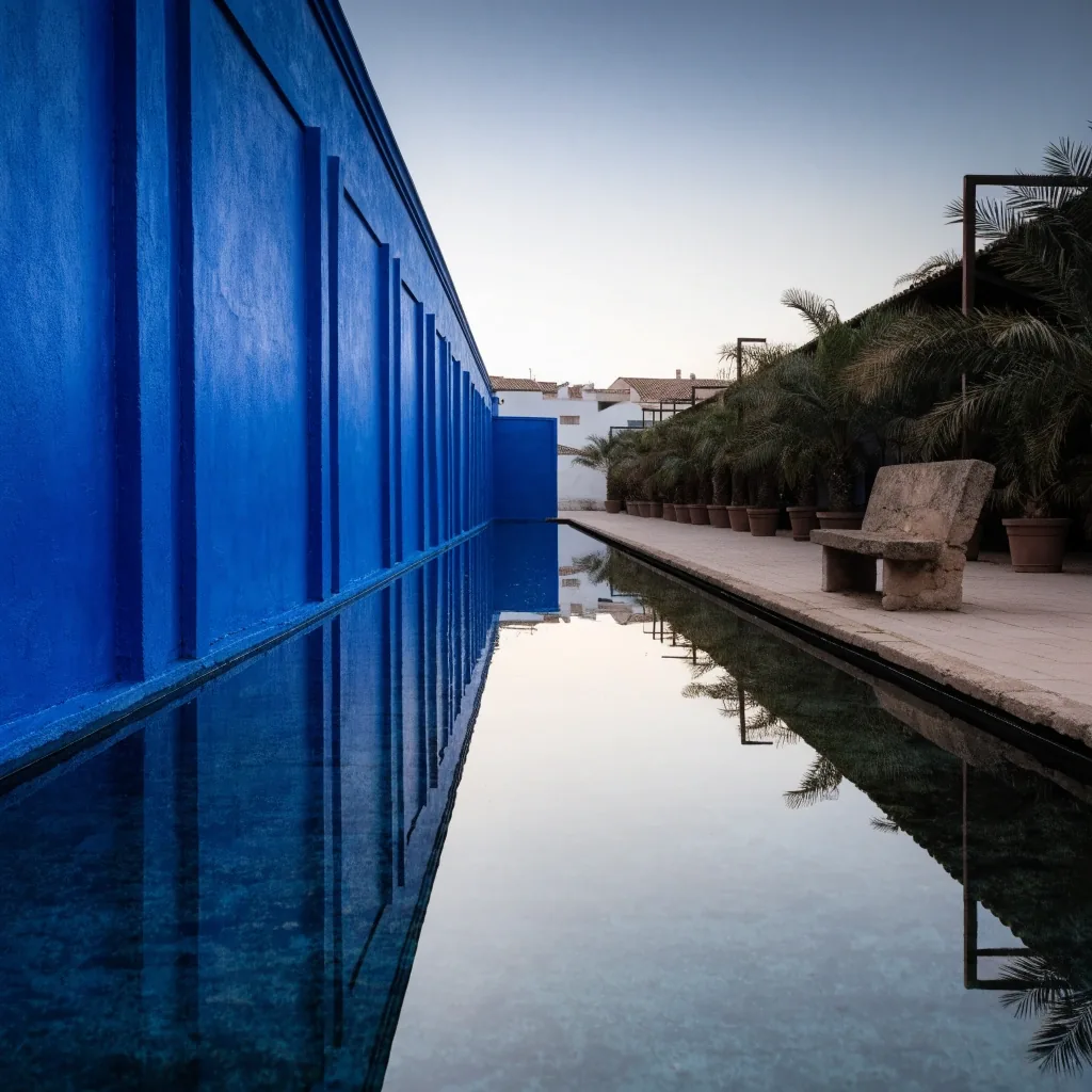 An empty bench along the pool edge at the Majorelle Garden in the morning