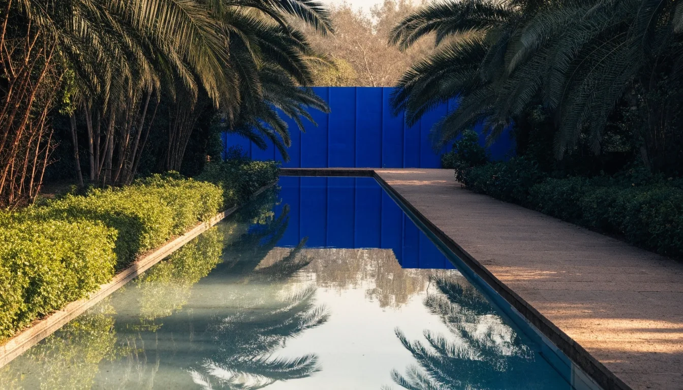 The long central pool of the Majorelle Garden reflecting the cobalt studio wall, with palm fronds above