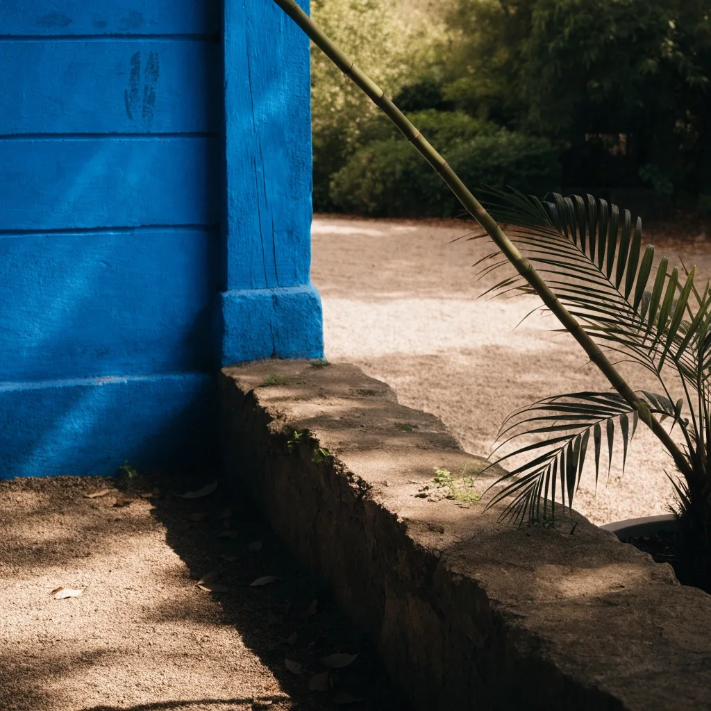 Shaded garden corner with a cobalt blue wall and potted palms in Marrakech afternoon light