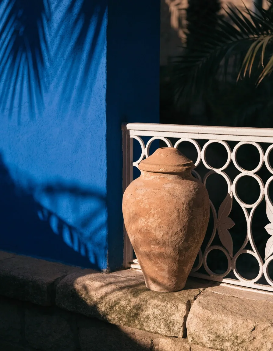 Cobalt-blue garden wall beside a white Art Deco railing in raking afternoon light