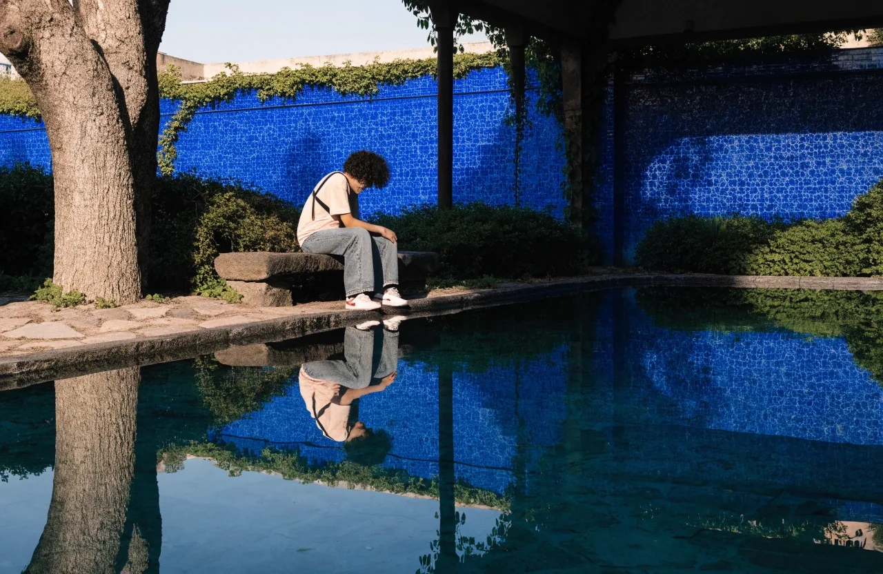 A shaded bench at the edge of the Majorelle Garden pool in the early morning light